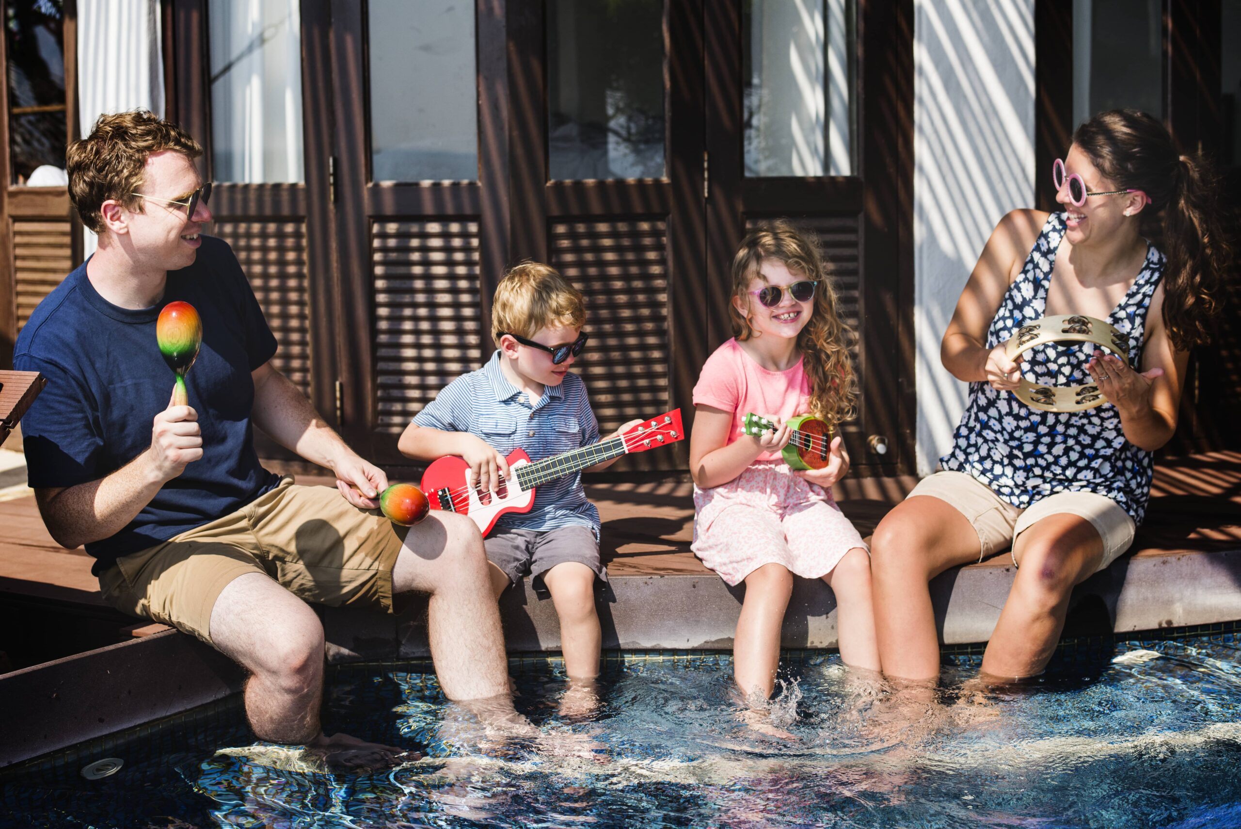Family staying cool and safe in a UAE hotel during the midday work ban by enjoying the shaded pool area